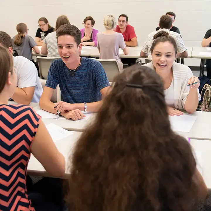 People seated and smiling in a room full of people